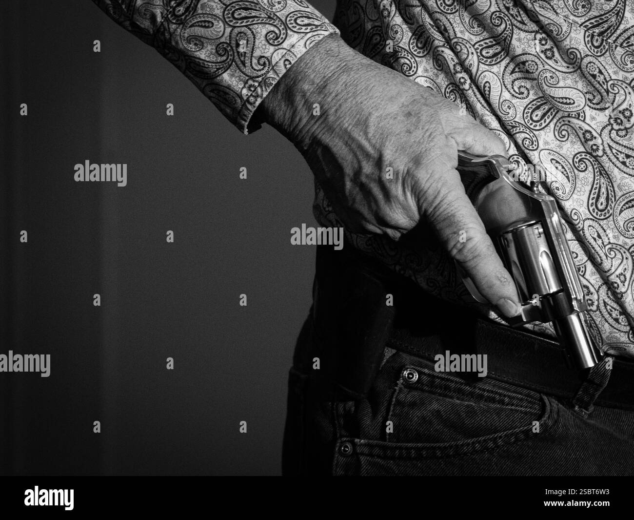 Ein Mann hält einen kleinen Nasenrevolver in der rechten Hand. Film Noir Schwarz-weiß-Stil. Stockfoto