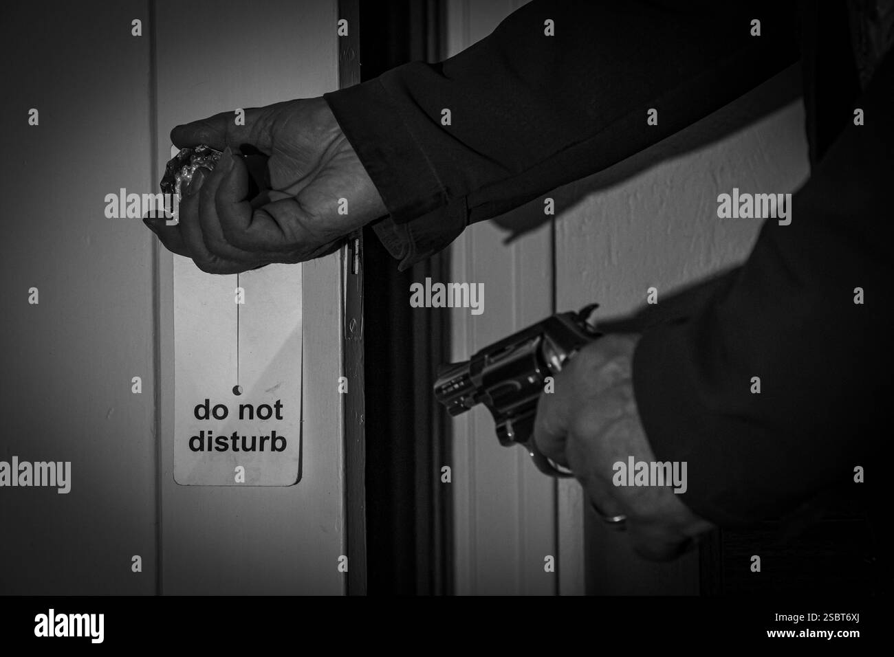 Ein Mann, der eine Tür öffnet, mit einem Nasenrevolver in der linken Hand. Film Noir-Stil in Schwarz-weiß. Stockfoto