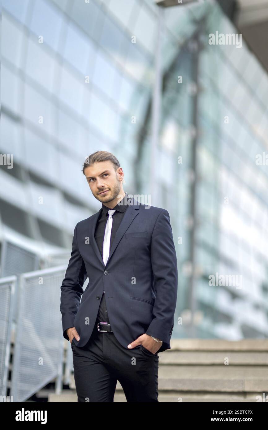 Hübscher, stilvoller junger Geschäftsmann, der im Freien ein Porträt posiert Stockfoto