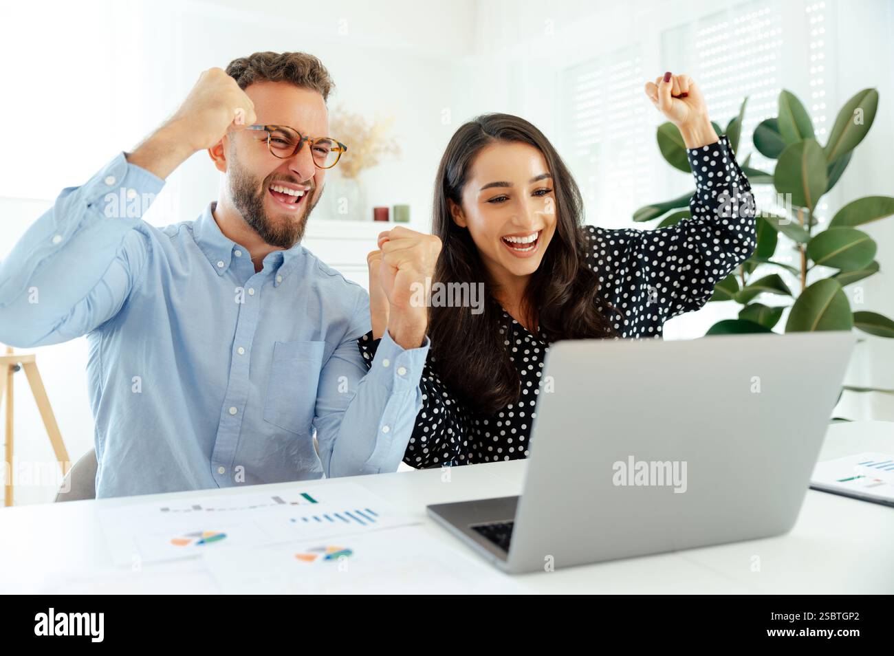 Zielerreichung, gute Arbeit. Fröhliches Geschäftsteam feiert Erfolg, multirassische Männer und Frauen, die mit Begeisterung Fäuste machen, Diagramme analysieren und Ziele erreichen, symbolisieren Erfolg und Zusammenarbeit Stockfoto