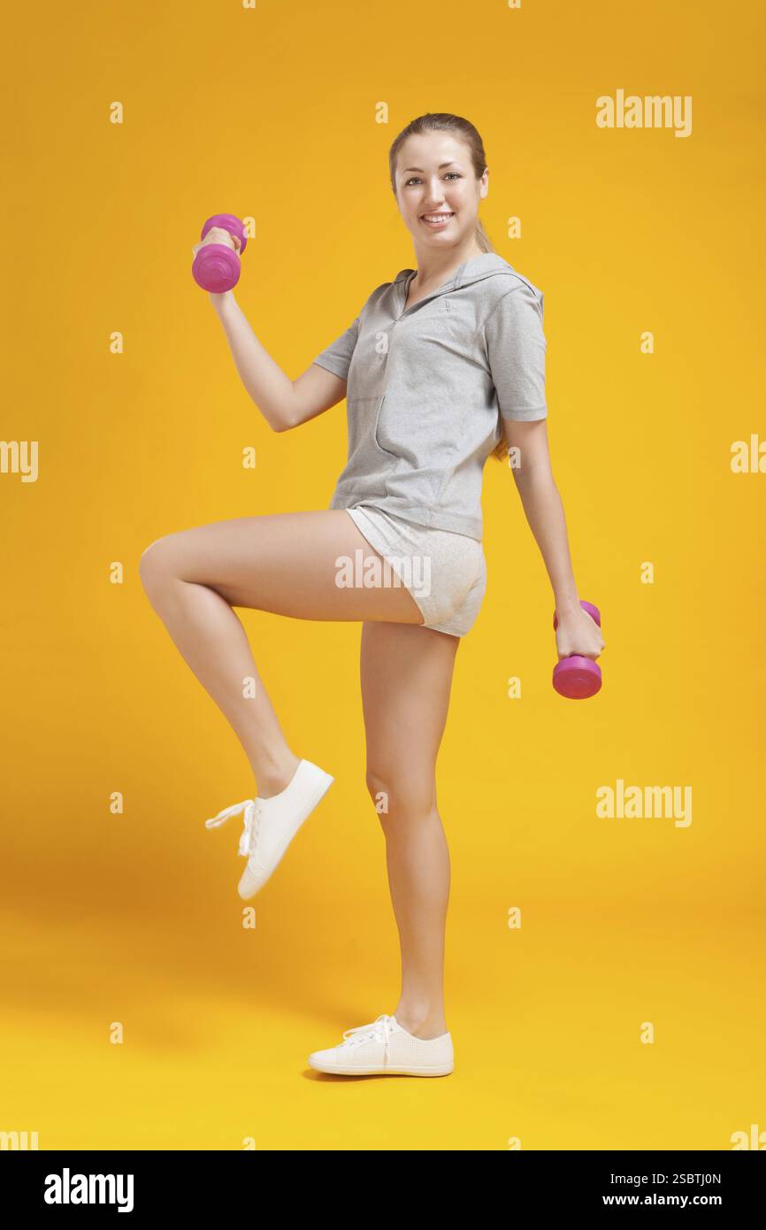 Junge blonde Fitness-Frau auf gelbem Hintergrund Stockfoto