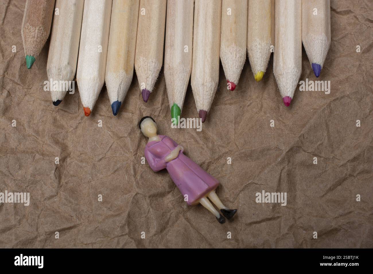 Buntstifte auf Papierhintergrund mit einer Frauenfigur Stockfoto