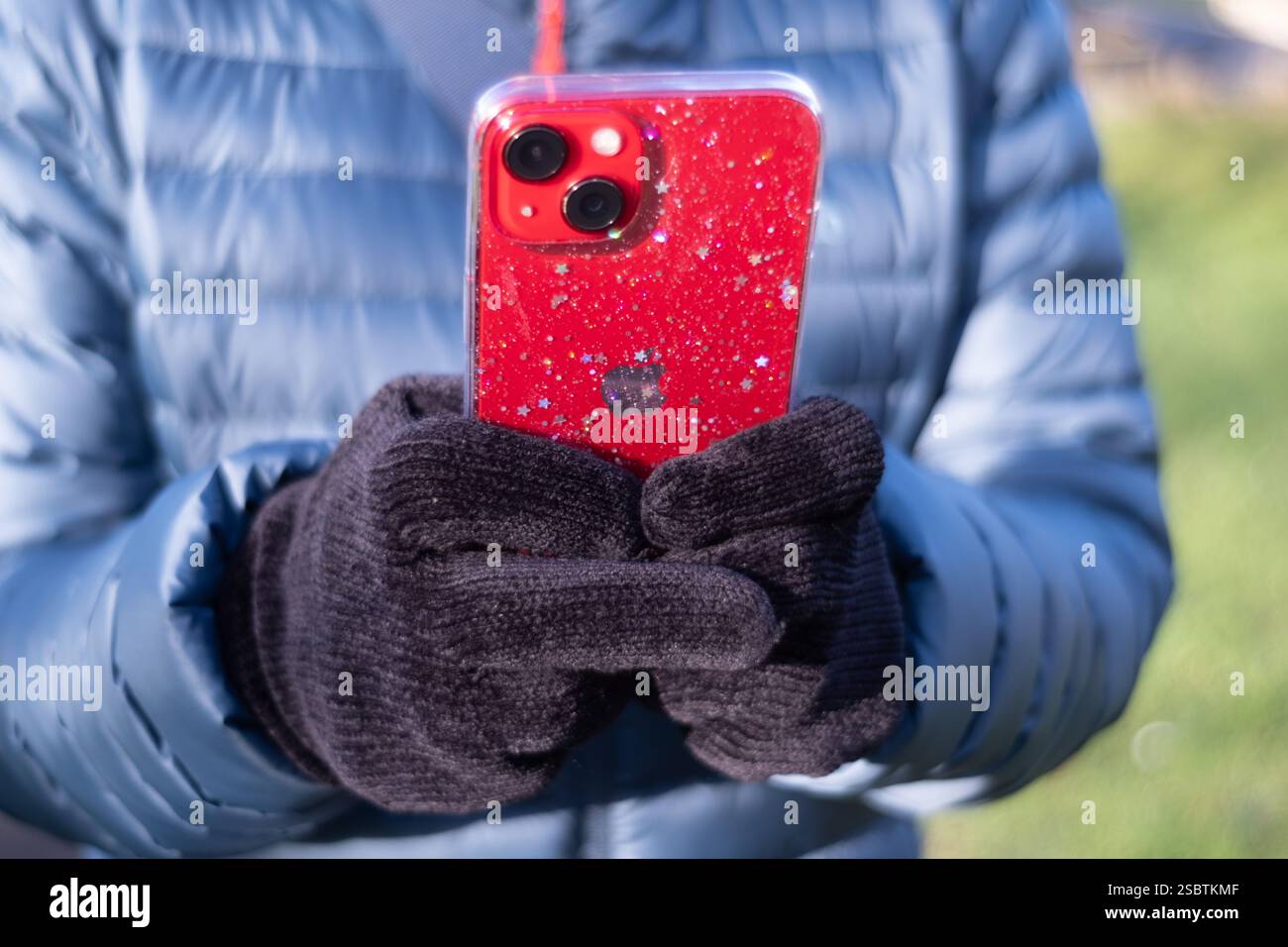 Bristol, Großbritannien. Eine Frau mittleren Alters, die bei kaltem Wetter im Freien ein Apple-Handy oder ein Apple-iphone benutzt. Sie schreibt, während sie das Telefon hält Stockfoto