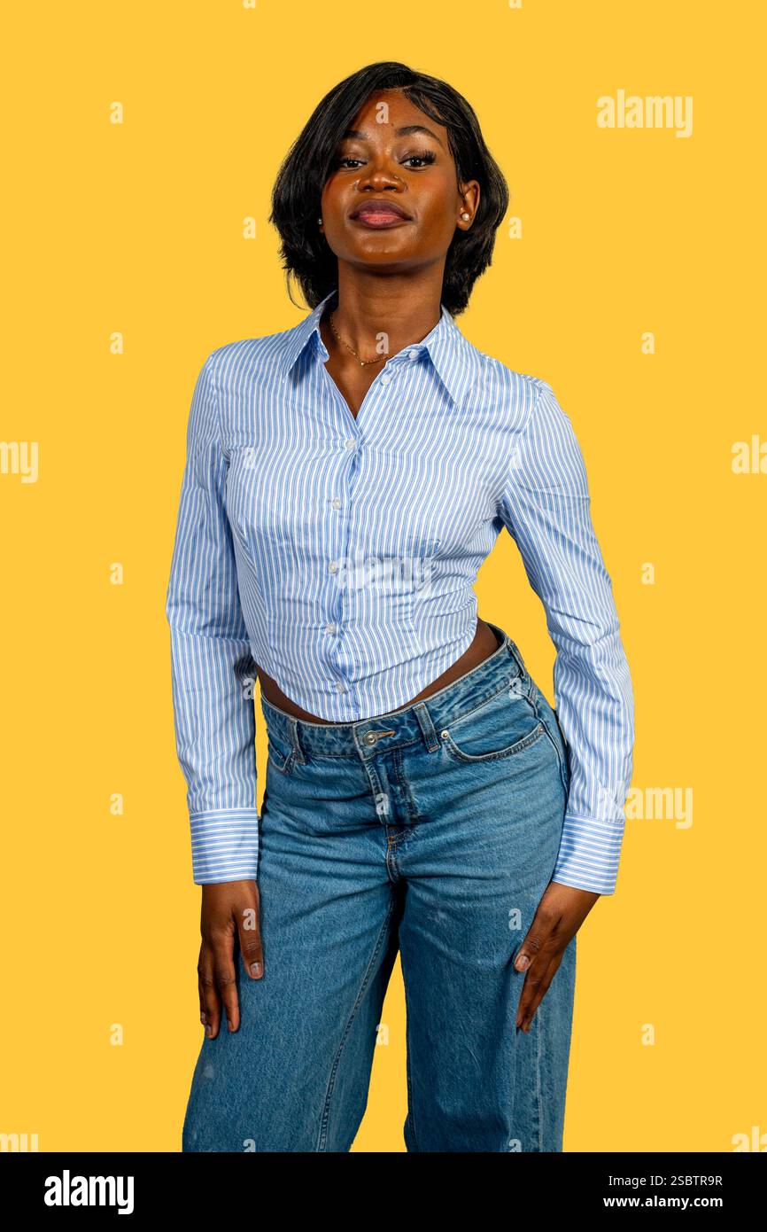 Studio-Porträt einer stilvollen jungen Frau, die vor einem leuchtend gelben Hintergrund Selbstvertrauen ausstrahlt Stockfoto