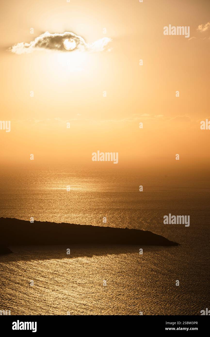 Die Sonne scheint durch eine Wolke über der Caldera von Santorin und der Insel Nea Kameni, Kykladen, Griechenland Stockfoto