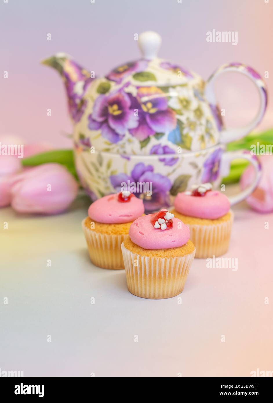 Teekanne mit Blumenmuster, Mini-Cupcakes und Tulpen für Oster- und Nachmittagstee; Konzept für Teestation, festliche Feiern, Geburtstage und Muttertag. Stockfoto