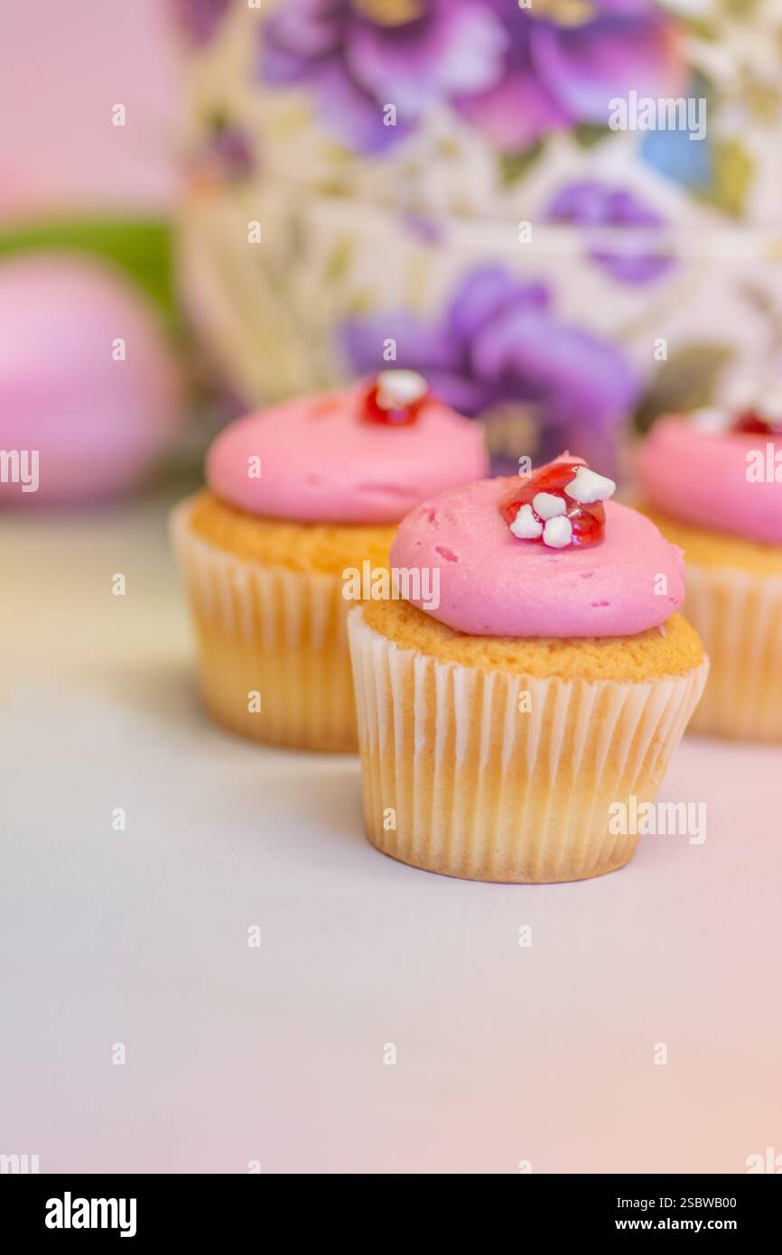 Teekanne mit Blumenmuster, Mini-Cupcakes und Tulpen für Oster- und Nachmittagstee; Konzept für Teestation, festliche Feiern, Geburtstage und Muttertag. Stockfoto