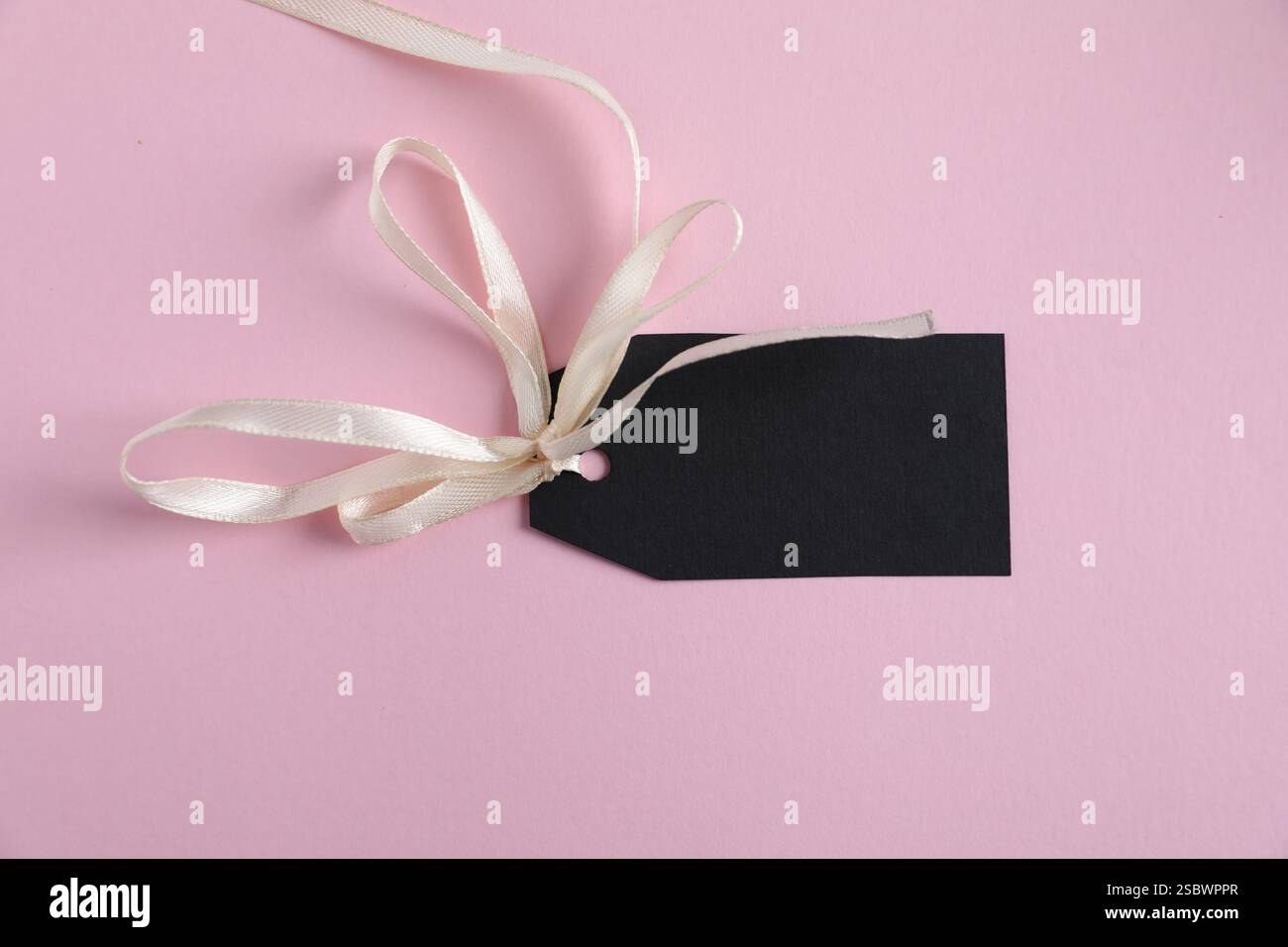 Leeres Etikett mit Band auf hellrosa Hintergrund, Draufsicht Stockfoto