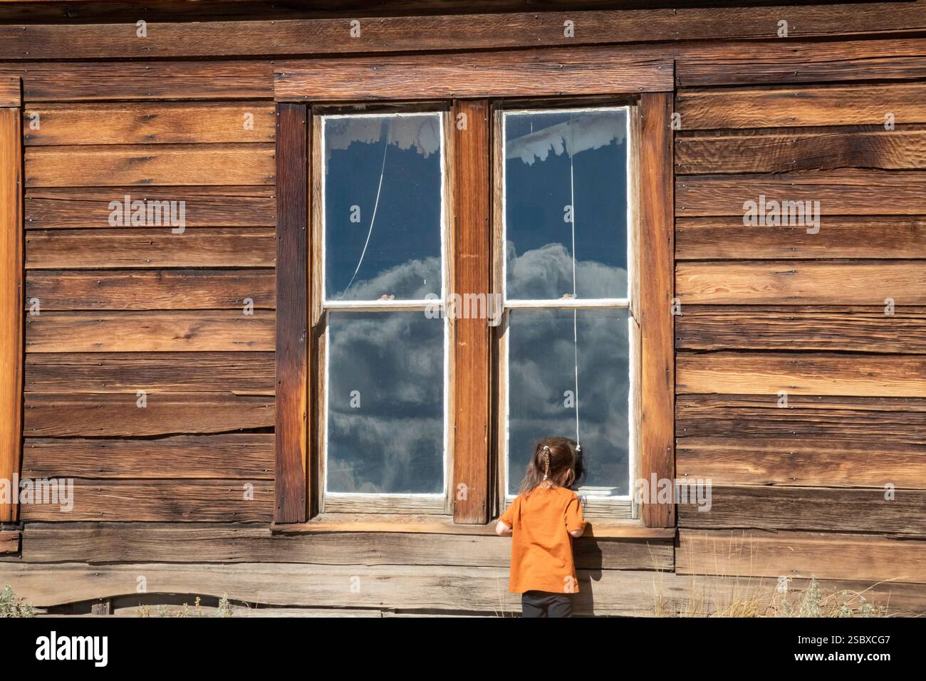 Bodie, Kalifornien: Ein Kind schaut in das Fenster des alten Schulhauses im Bodie State Historic Park. Der Park bewahrt die Überreste eines Goldbergbaus Stockfoto