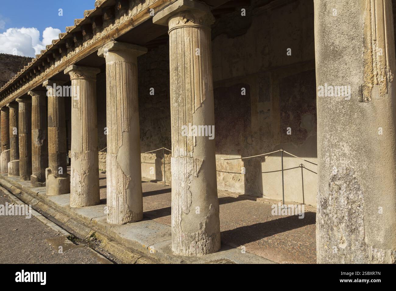 Altes großes Gebäude, das mit Terrakotta-Tonziegeln bedeckt und von Steinsäulen gestützt ist, an den antiken Ruinen von Pompeji, Region Kampanien, Italien, EUR Stockfoto
