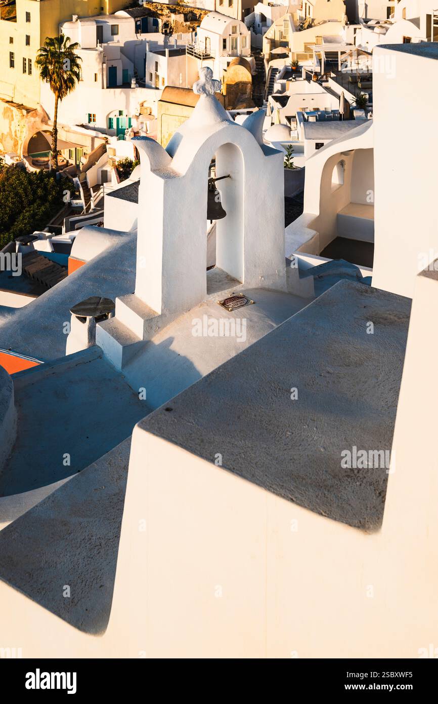 Blockhäuser und ein Glockenturm von Oia im warmen Licht der Morgensonne, Santorin, Griechenland Stockfoto