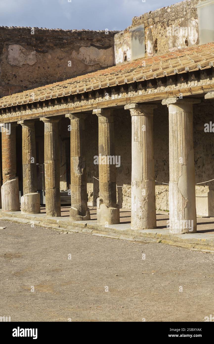 Altes großes Gebäude, das mit Terrakotta-Tonziegeln bedeckt und von Steinsäulen gestützt ist, an den antiken Ruinen von Pompeji, Region Kampanien, Italien, EUR Stockfoto