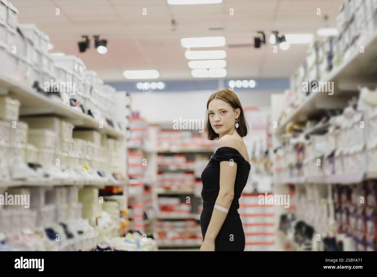 Frau in einem Sneaker-Gang in einem Laden, in einem schwarzen Kleid Stockfoto