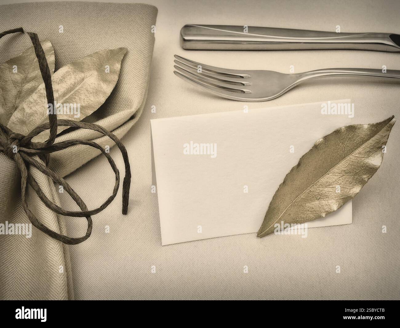 Tisch Mit Golden Bay Leaves In Serviette Und Cord In Der Nähe Von Knife, Fork Und Gästekarte In Beige Stockfoto