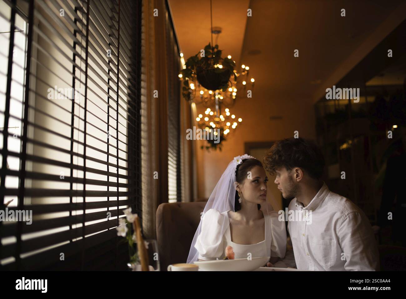 Braut und Bräutigam teilen einen intimen Blick in einem romantischen Café Stockfoto