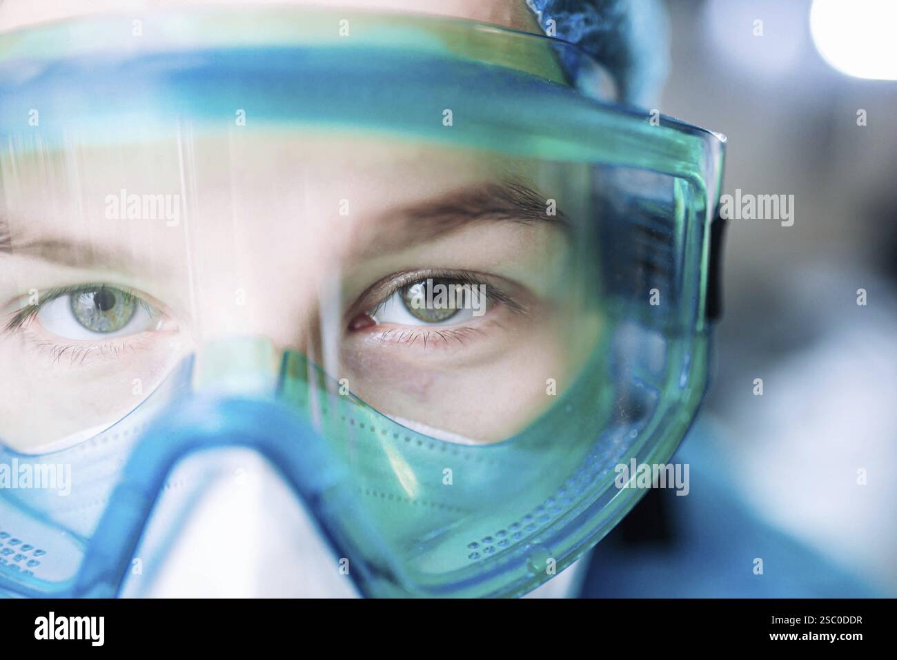 Medizinisches Fachpersonal trägt Schutzbrille und Maske, fokussierter Blick in einer detaillierten Nahaufnahme Stockfoto