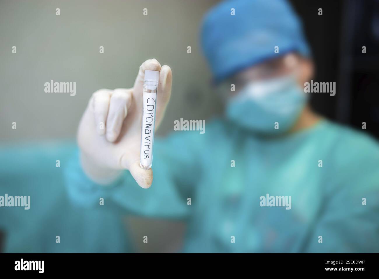 Person hält ein mit Coronavirus gekennzeichnetes Reagenzglas in einer medizinischen Umgebung Stockfoto