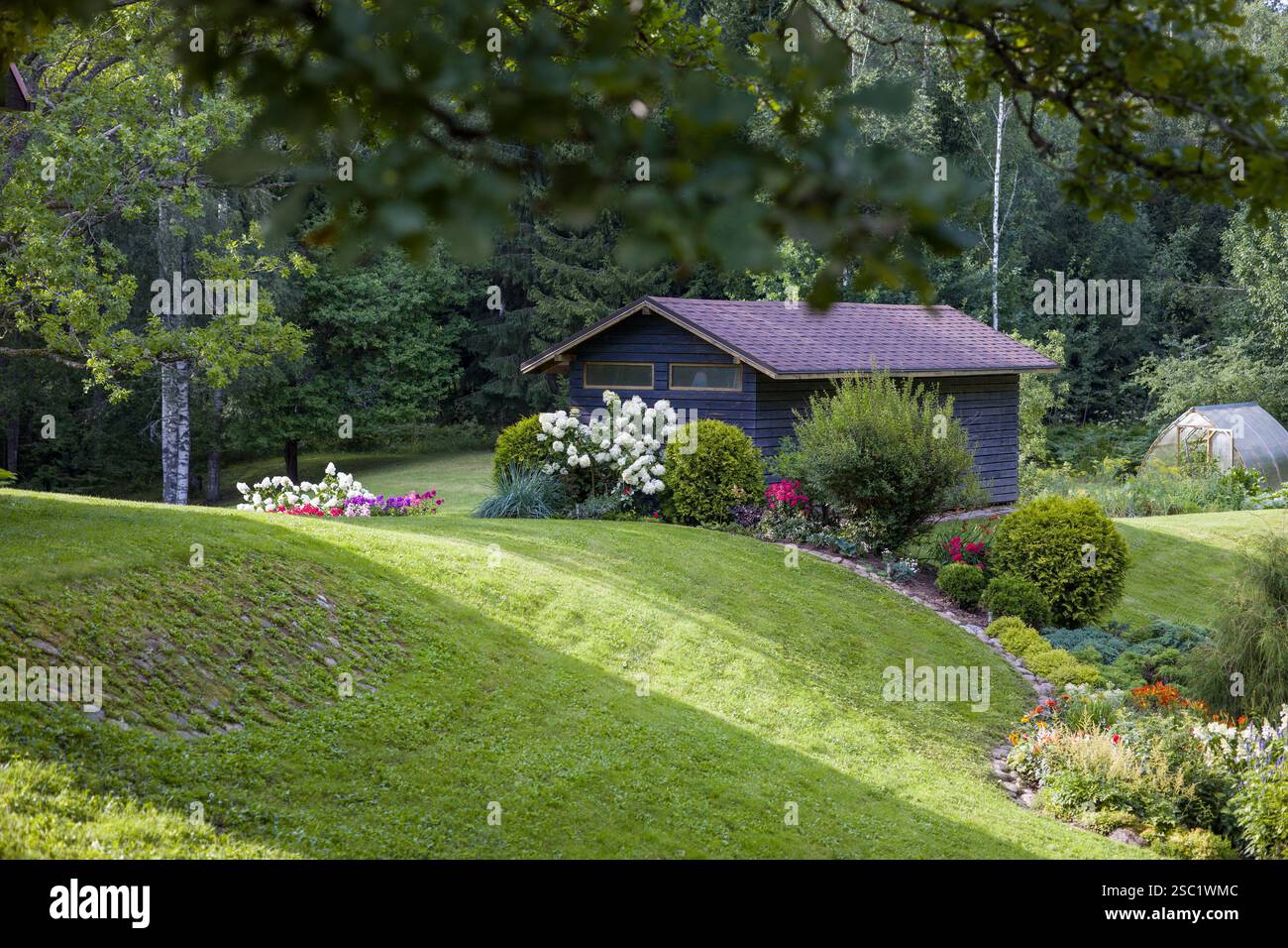 Wunderschöner Garten im Hinterhof mit einer Vielzahl von blühenden Pflanzen und Sträuchern. Gepflegte Landschaftsgestaltung schafft einen farbenfrohen und einladenden Raum. Perfekt für Stockfoto