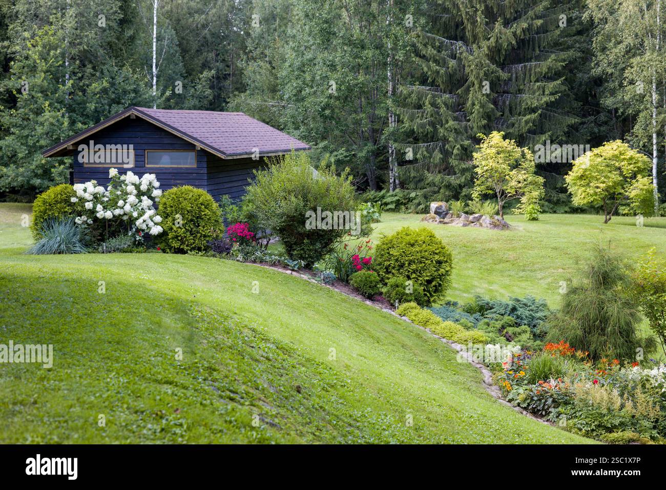Wunderschöner Garten im Hinterhof mit einer Vielzahl von blühenden Pflanzen und Sträuchern. Gepflegte Landschaftsgestaltung schafft einen farbenfrohen und einladenden Raum. Perfekt für Stockfoto