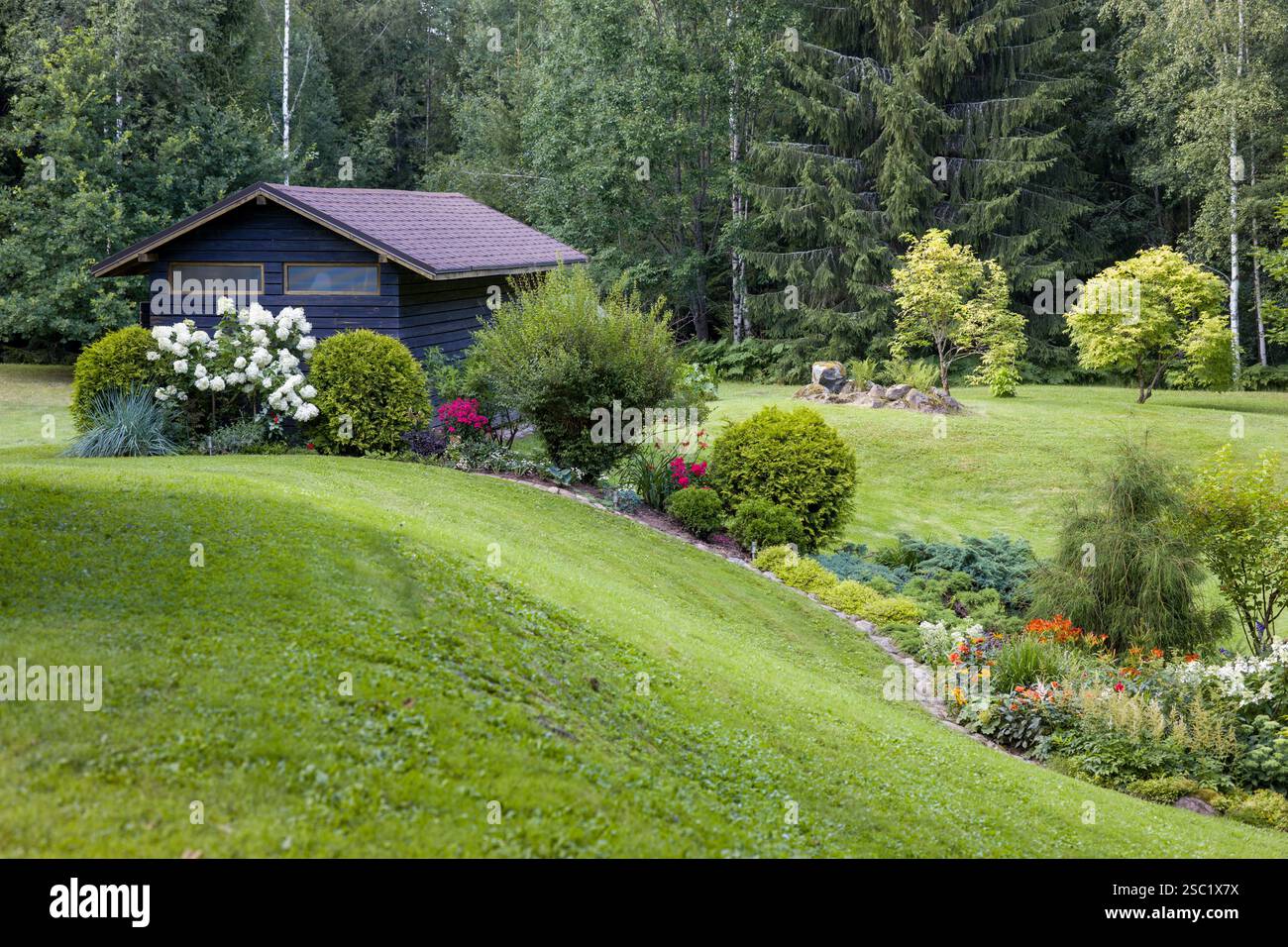 Wunderschöner Garten im Hinterhof mit einer Vielzahl von blühenden Pflanzen und Sträuchern. Gepflegte Landschaftsgestaltung schafft einen farbenfrohen und einladenden Raum. Perfekt für Stockfoto