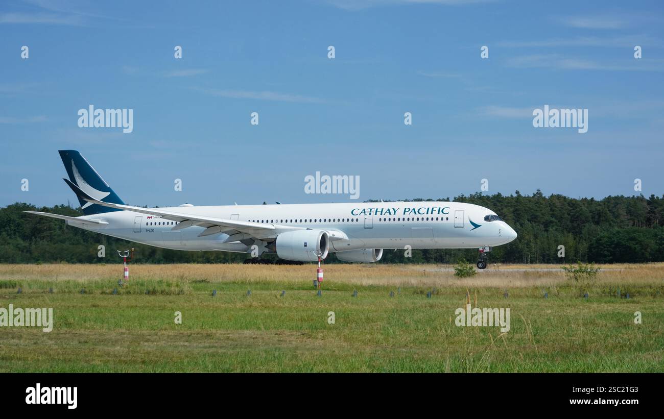Airbus A350-941 der Fluggesellschaft 'Cathay Pacific' auf der Landebahn 18 West während des Starts vom Flughafen Frankfurt (FRA) an einem sonnigen Tag. Blick auf die Start- und Landebahn Stockfoto
