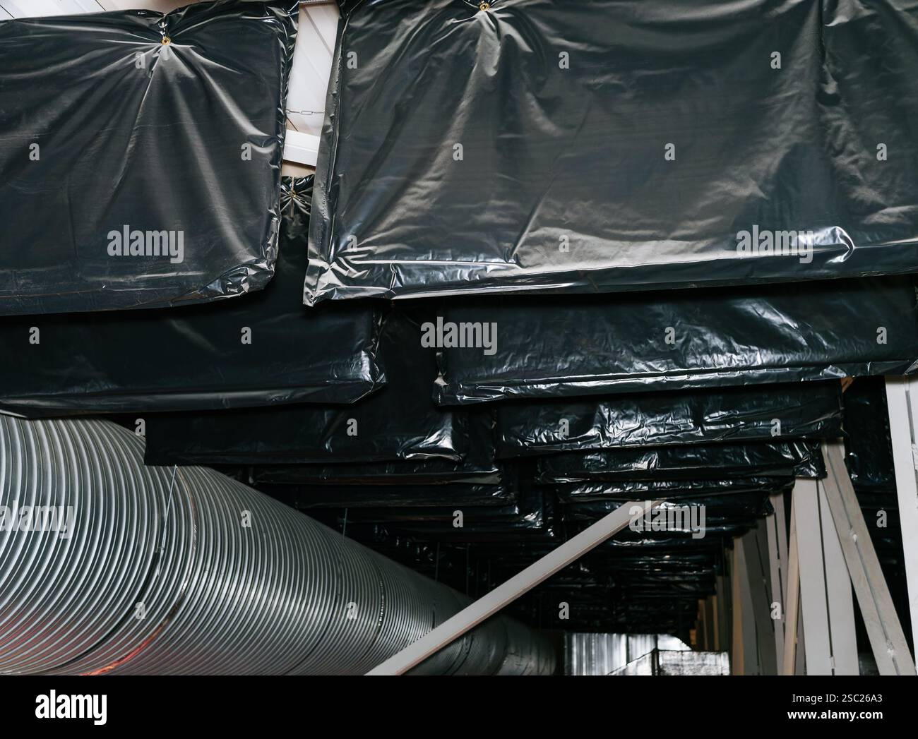 Nahaufnahme von Schallabsorptions- und Schalldämmpaketen, die an den Metallträgern der hohen Decke der Arena angebracht sind, um den Schallparameter zu verbessern Stockfoto