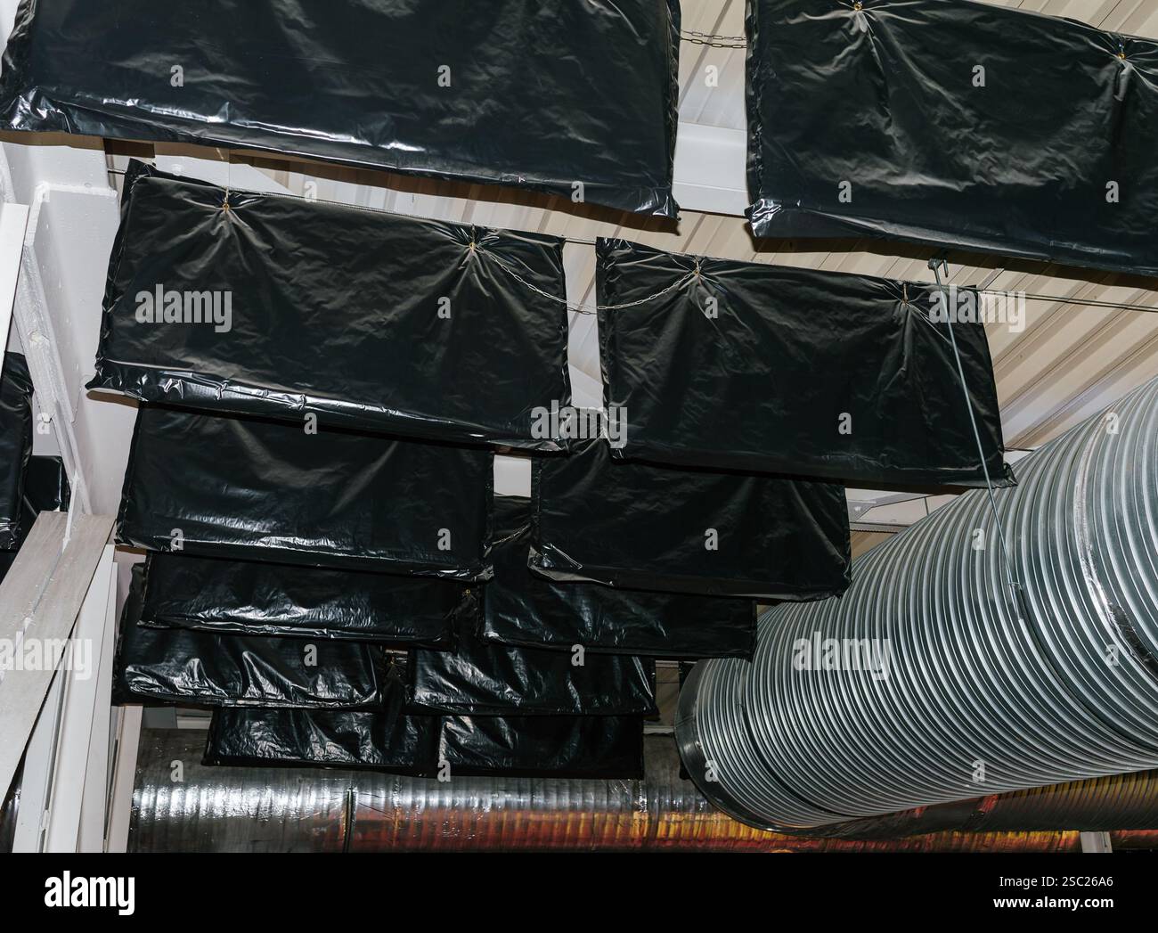 Ansicht der Schallabsorptions- und Schalldämmpakete, die an den Metallträgern der hohen Decke der Arena angebracht sind, um die Schallparameter zu verbessern. Stockfoto