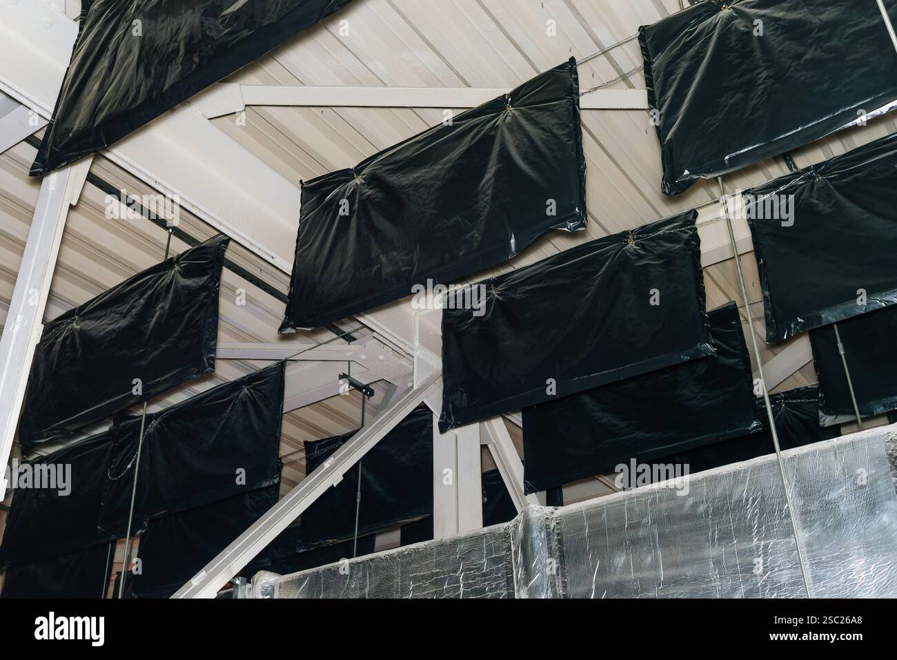 Schallabsorptions- und Schalldämmpakete, die an der hohen Metalldecke angebracht sind, um die Schallparameter zu verbessern. Stockfoto