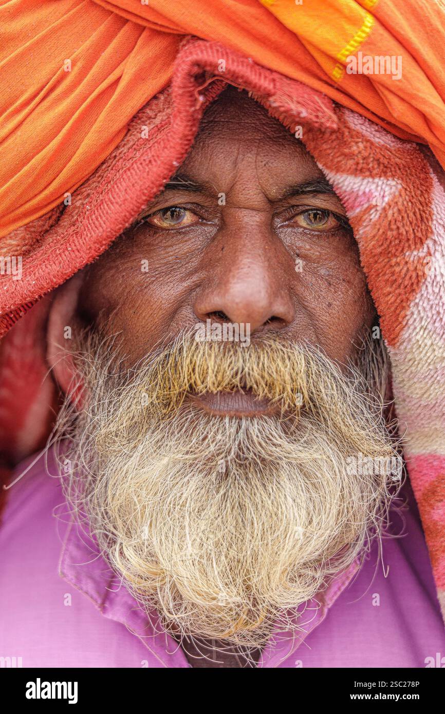 Eine Nahaufnahme eines bärtigen Sadhu, sein Gesicht ruhig und konzentriert, mit Decken über seinem Kopf, die Frieden und spirituelle Einsamkeit symbolisieren. Stockfoto