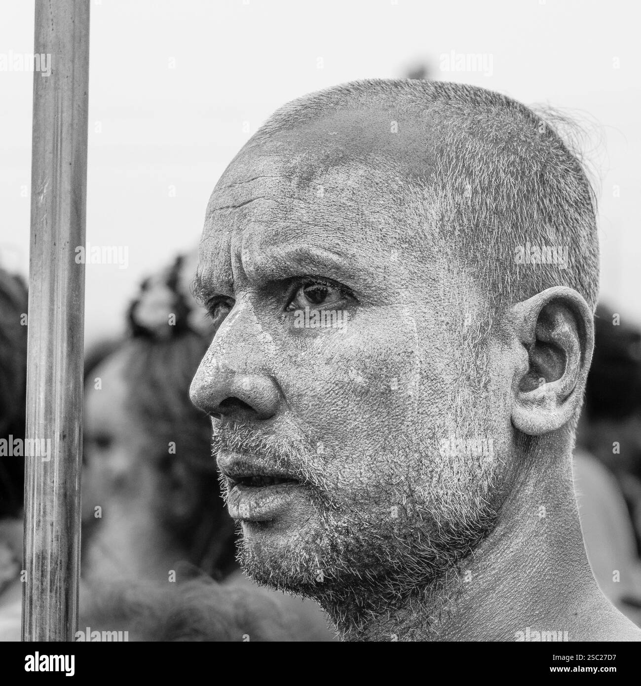 Ein Naga Sadhu, mit einem seltsamen, fernen Blick auf das heilige Bad, verloren in tiefer Besinnung, verkörpert die Mystik und Transformation seines spirituellen Stockfoto