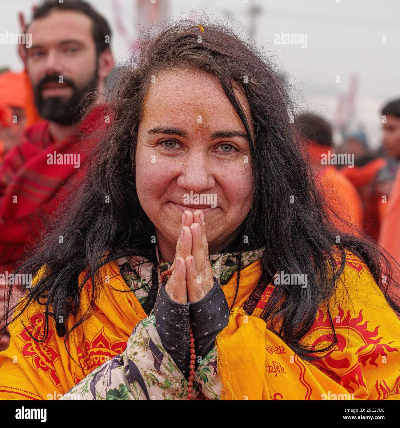 Eine ausländische, geweihte Frau geht in Richtung Sangam, ihr Herz erfüllt von Ehrfurcht, bereitet sich auf das heilige Bad vor und nimmt das spirituelle Wesen auf. Stockfoto