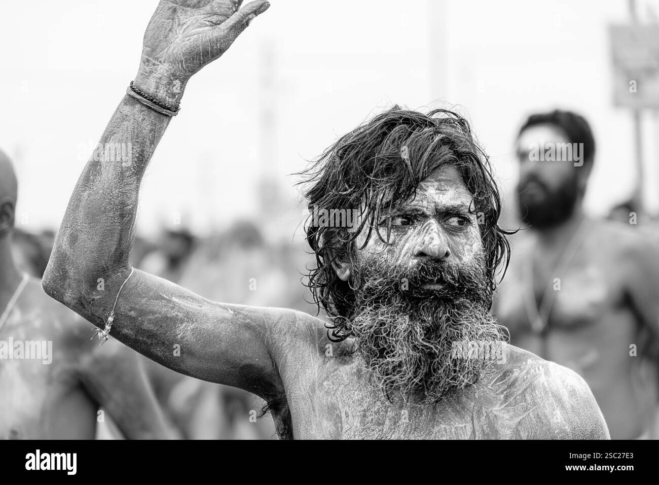 Ein Naga Sadhu, mit einer Hand hoch nach dem heiligen Bad, verkörpert göttliche Energie und spirituellen Triumph und strahlt Frieden und Kraft aus. Stockfoto