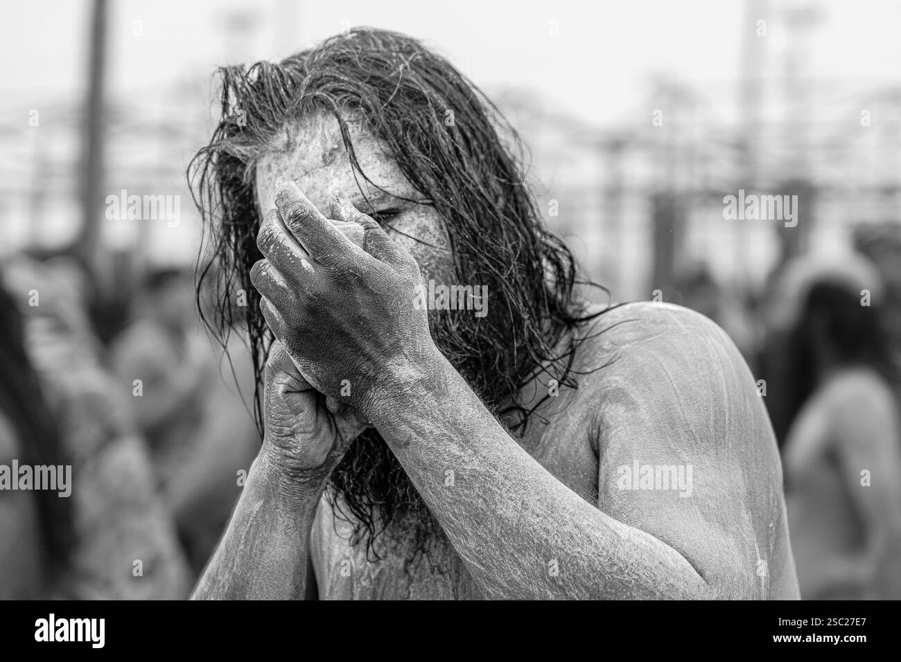 Ein Sadhu, frisch gebadet in heiligem Wasser, hält ein Ganja in der Hand, sein Ausdruck friedlich und doch transzendent, symbolisiert tiefe spirituelle Verbindung. Stockfoto