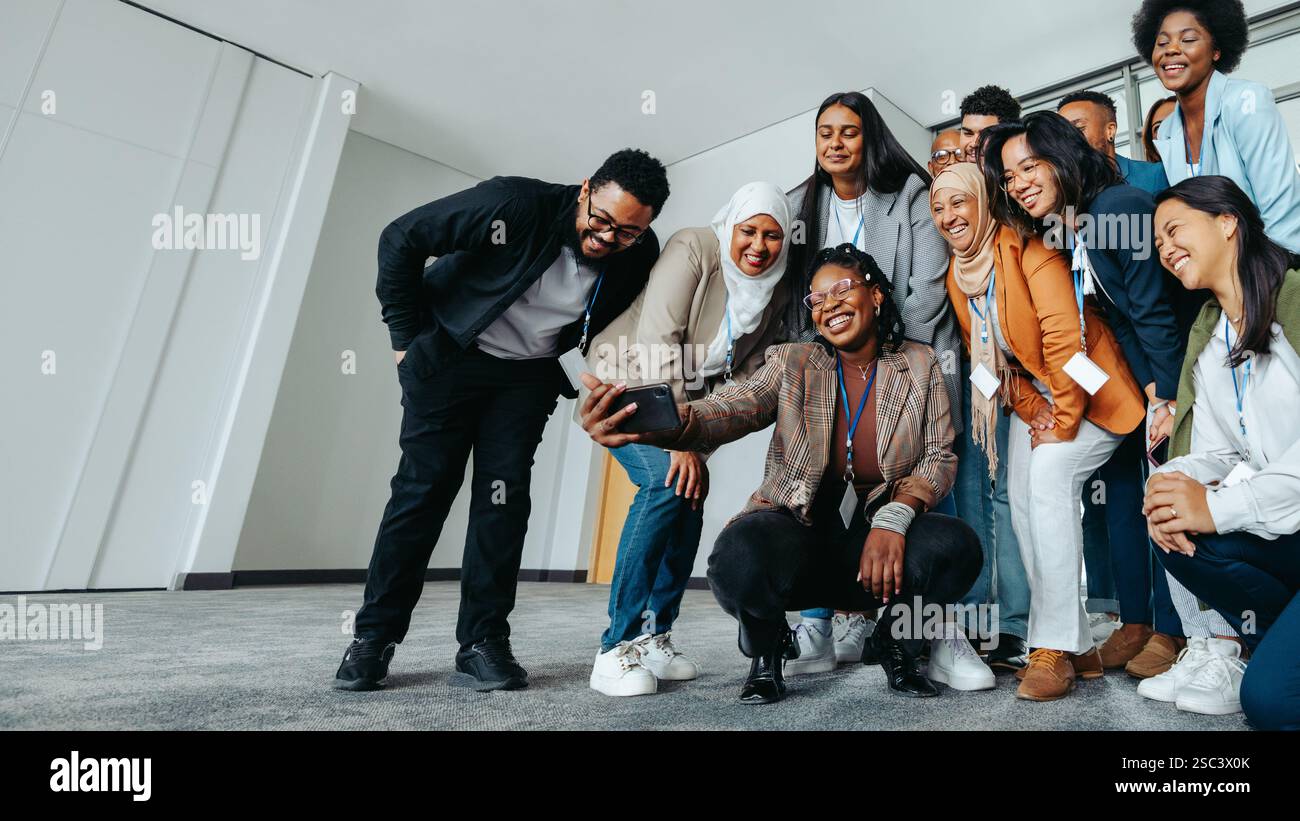 Verschiedene Gruppen von Kollegen genießen einen lustigen Moment zusammen, während sie während einer Teamsitzung im Büro ein Selfie machen. Stockfoto