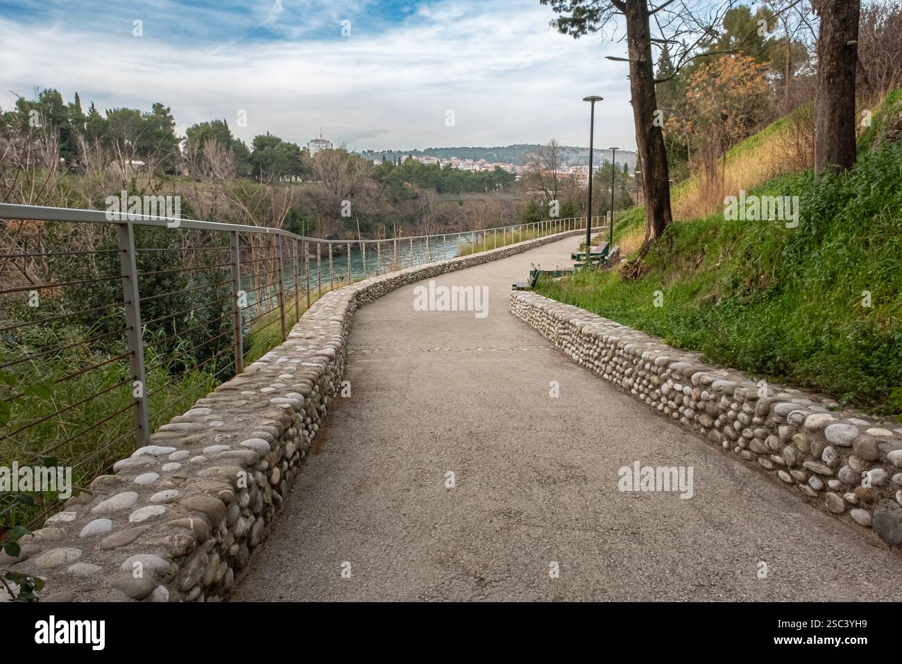 Gehweg in einem Stadtpark. Wunderschöner Wanderweg im Park für einen Spaziergang. Ein malerischer Pfad durch den Park mit Fluss. Reisefoto, niemand Stockfoto