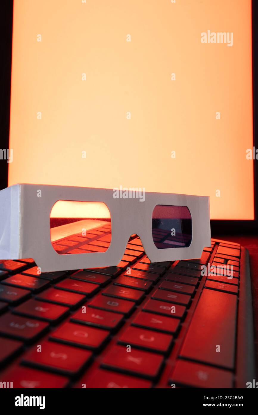 3D-Retro-Brille auf einer Tastatur mit rotem Hintergrund. Stockfoto