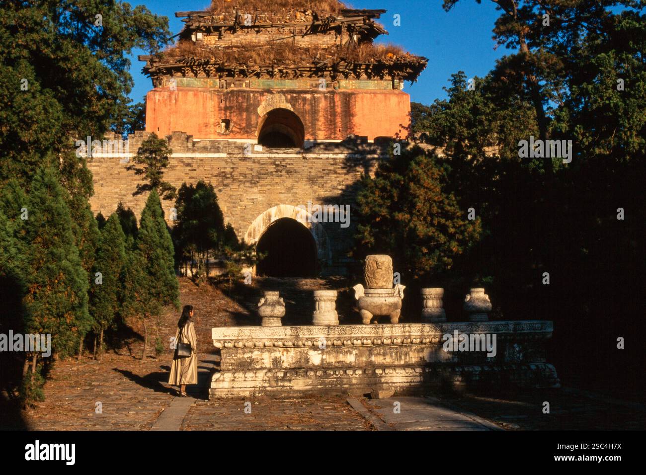 Ein historisches Tor inmitten von Bäumen in Hebei, China, mit einer Person in der Nähe. Stockfoto