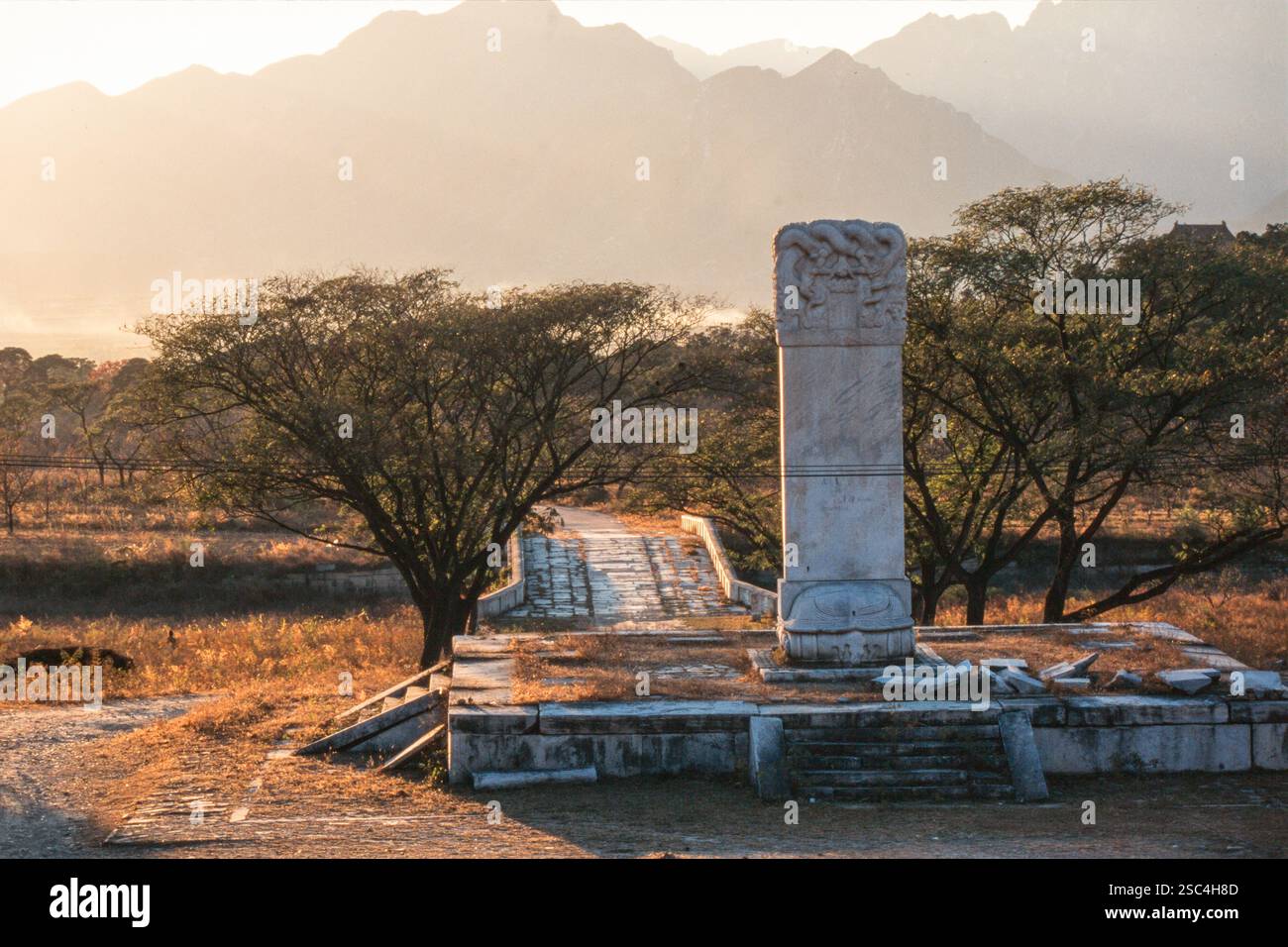 Altes Steindenkmal in Äthiopien mit fernen Bergen und Bäumen bei einem warmen Sonnenuntergang. Stockfoto