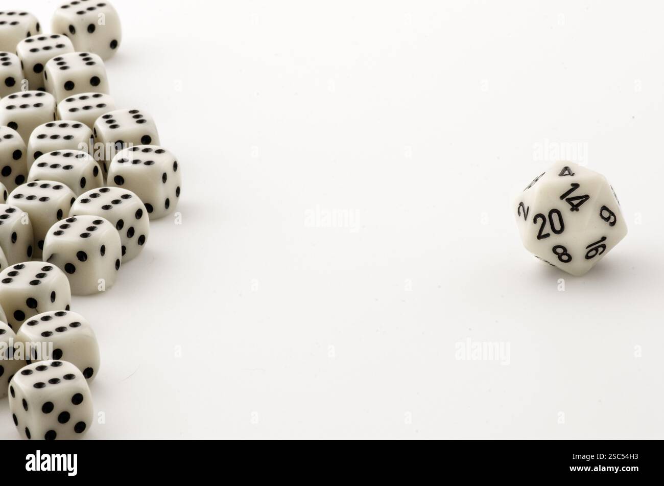 Ein einsamer weißer, zwanzigseitiger Würfel steht neben einer Gruppe von sechs-seitigen Würfeln und symbolisiert Individualität und Zufall beim Tabletop-Gaming. Stockfoto