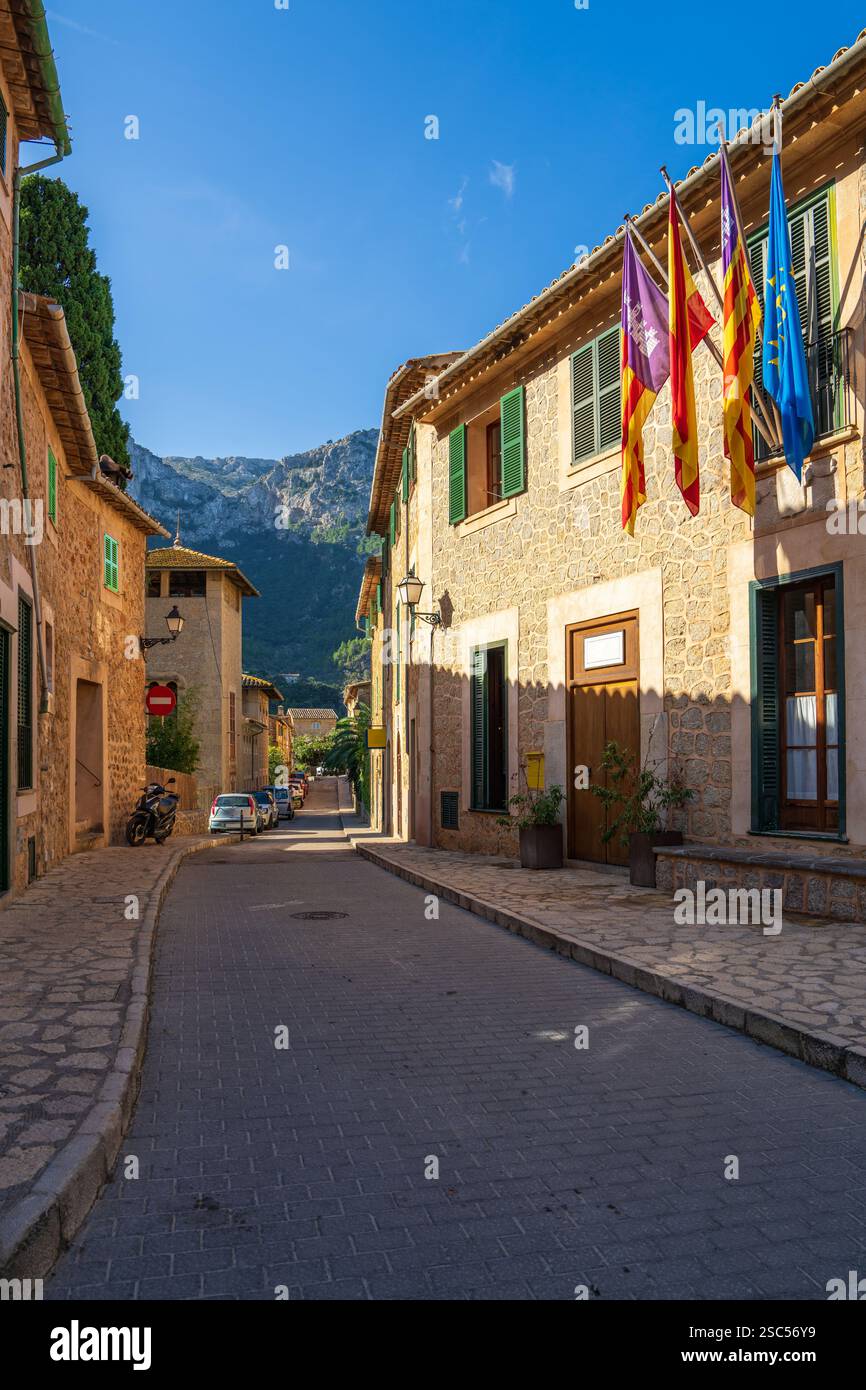Enge Straße im Dorf Deia, Mallorca, gesäumt von rustikalen Steinhäusern. Fenster mit vielen bunten Fahnen dekoriert. Balearen, Spanien Stockfoto