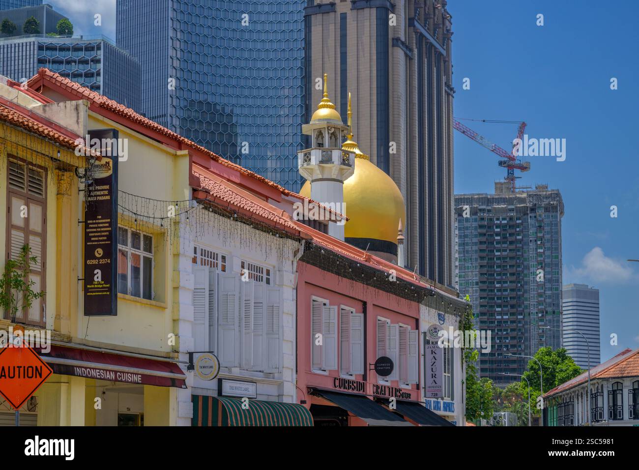 Die goldenen Kuppeln und das schlanke Minarett der Sultan-Moschee von Kampong Glam ragen über die farbenfrohen Geschäfte der North Bridge Road. Stockfoto