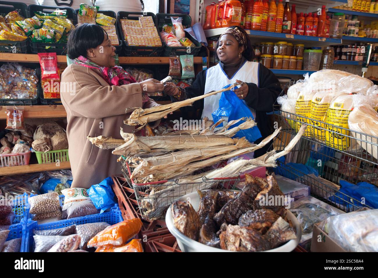 Zwei Frauen tauschen Waren und Geld auf einem lokalen Markt in Harare, Simbabwe. Stockfoto