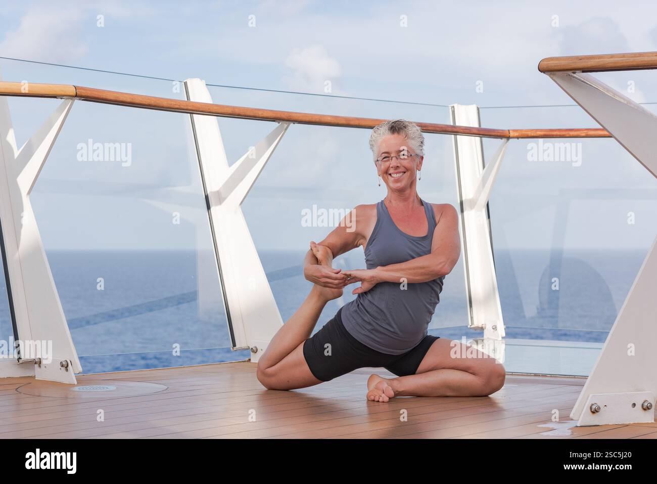 Starke, fitte, reife Frau, die beim Anschlagen von strenuos Yoga draußen auf dem Schiffsdeck posiert. Stockfoto