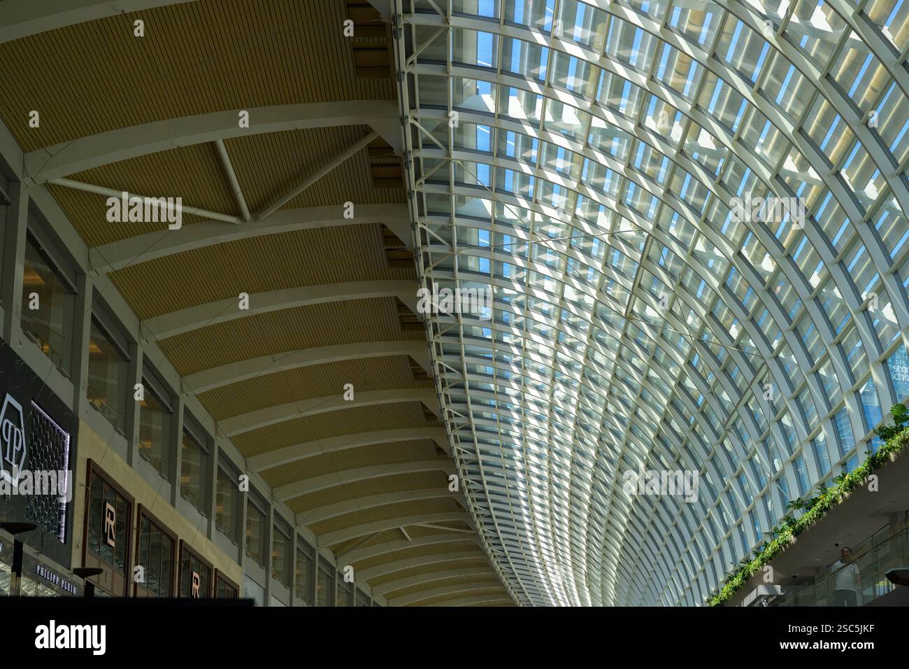 Detail des geschwungenen Stahl- und Glasdachs auf den Shoppes at Marina Bay Sands Luxus Shopping Centre am Fuße des berühmten Singapur Hotels. Stockfoto