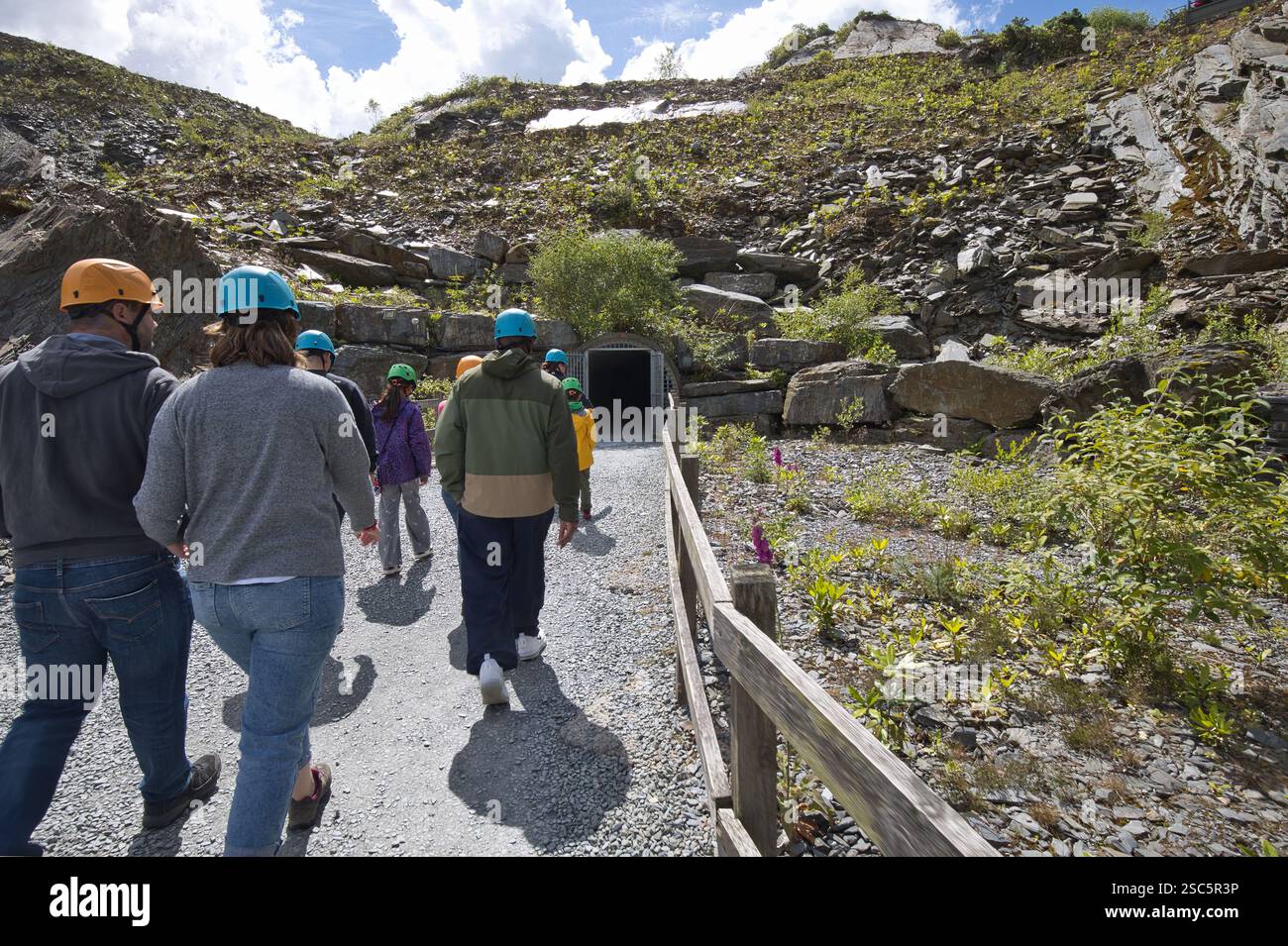 Wales, Gwynedd, Llechwedd - 08. Juli 2024: Besucher der geführten Deep Mine Tour auf dem Weg in die Untertage der alten Schiefermine. Stockfoto