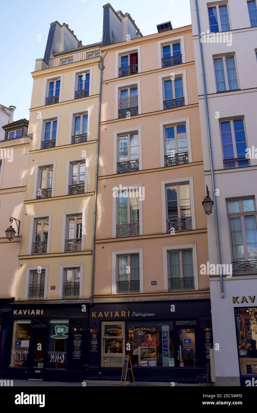 Paris, Frankreich, 02.03.2025. Pastellrosa, gelb und orange Gebäude im 4. Arrondissement von Paris. Straßenszene. Stockfoto