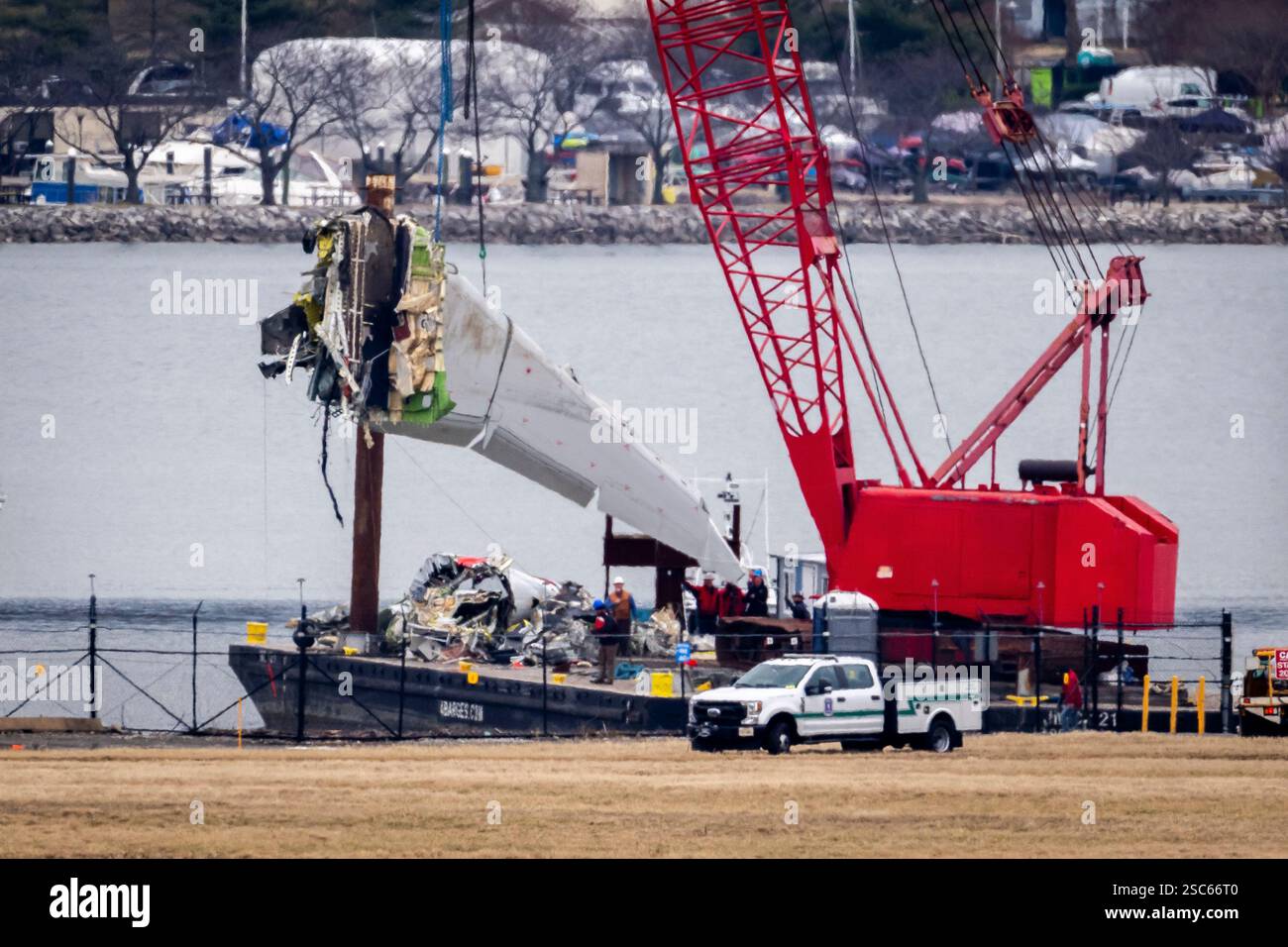 A crane offloads a piece of wreckage from a salvage vessel onto a ...
