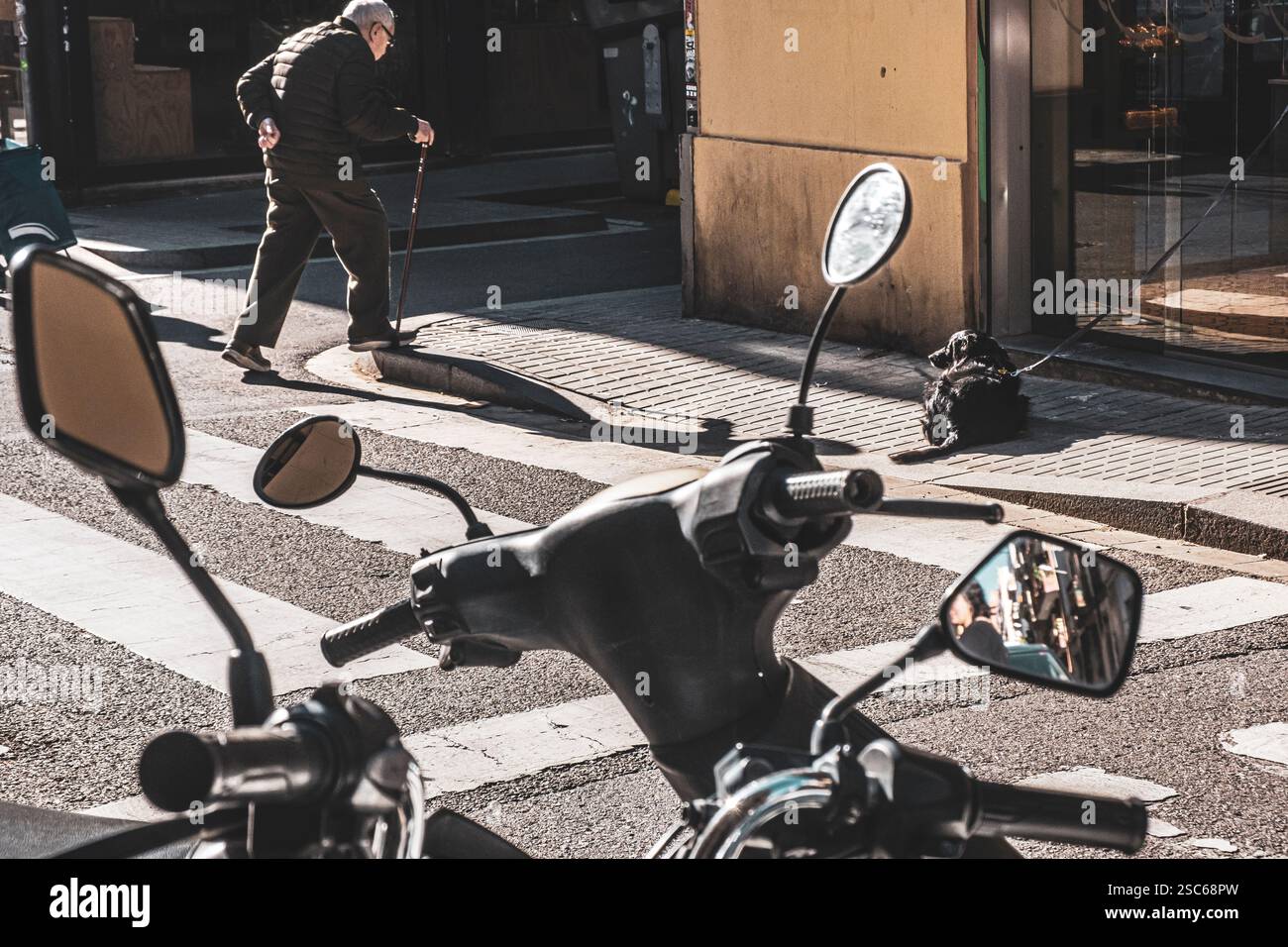 Ein alter Mann mit einem Stock überquert eine Straße im Zentrum von Barcelona, Spanien Stockfoto