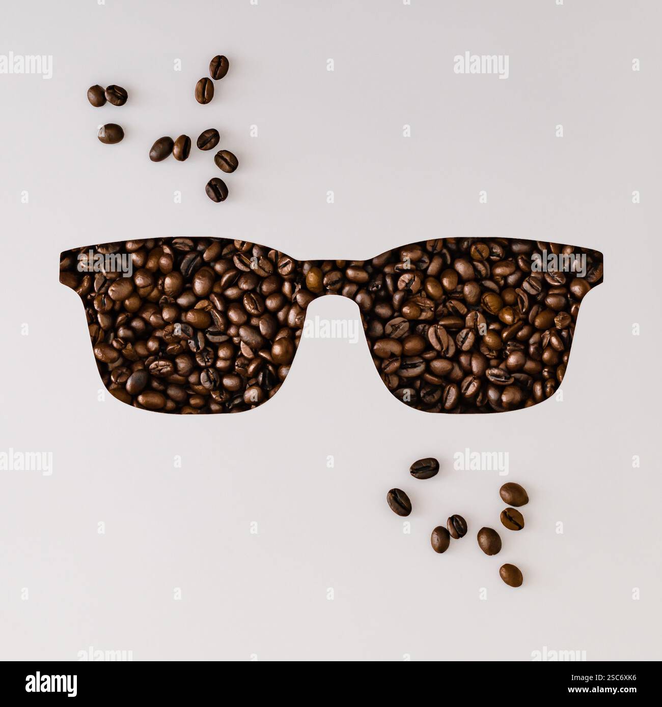 Kaffeebohnen sichtbar durch einen gläsernen Ausschnitt auf weißem Hintergrund. Minimales Kaffeekonzept. Kaffeeästhetik. Flache Lage, Draufsicht. Stockfoto