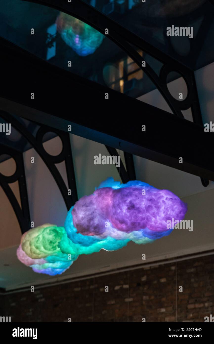 Leuchtende, farbenfrohe Formationen, die Wolken ähneln, hängen unter einer dekorativen Struktur. Stockfoto